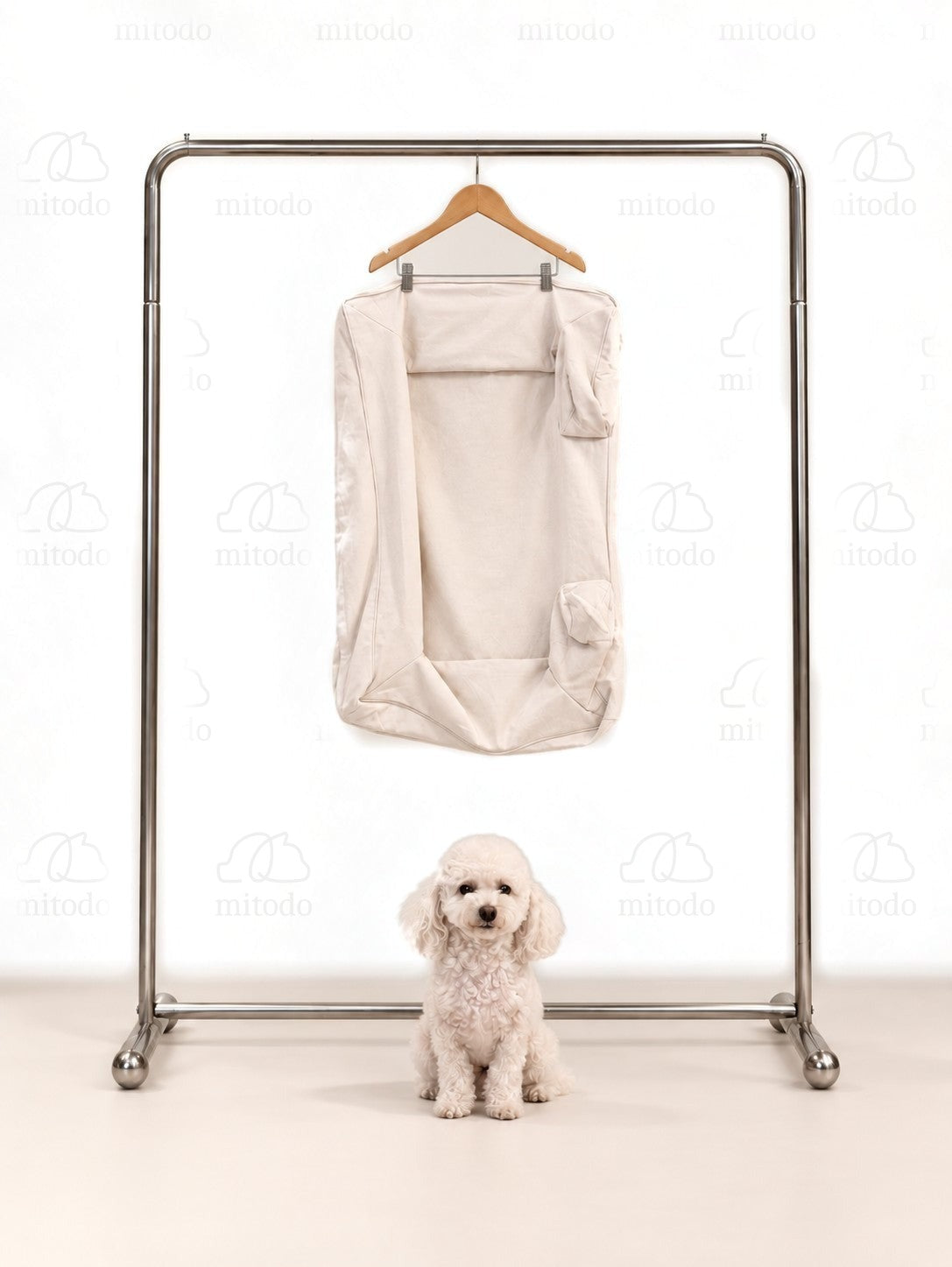 Kumo Bed Extra Cover in Cream hanging on a rail, with a white poodle sitting below