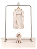 Mitodo Kumo Bed Extra Cover in Cream hanging on a rail, with a white poodle sitting below